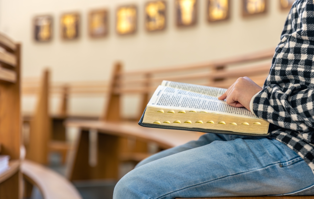 Focused Bible reading among empty pews. Bible in church.